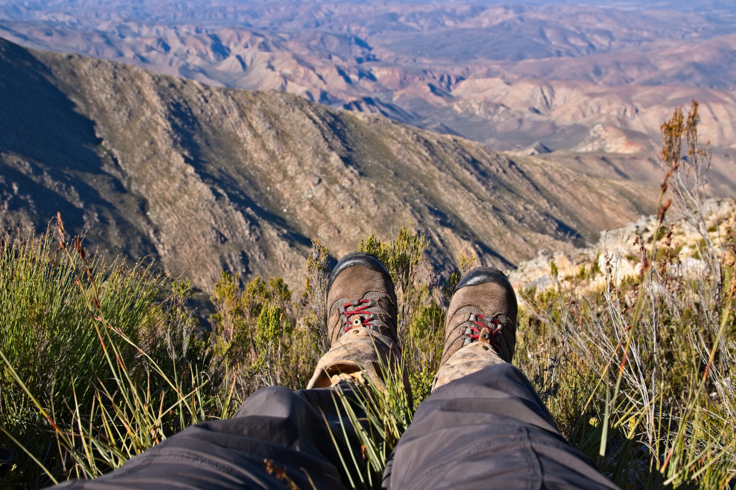 high-angle-shot-person-s-feet-sitting-top-hill-beautiful-valley